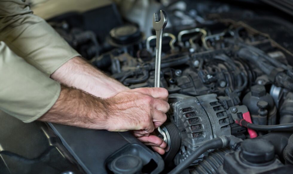 Hands of mechanic servicing a car in repair garage